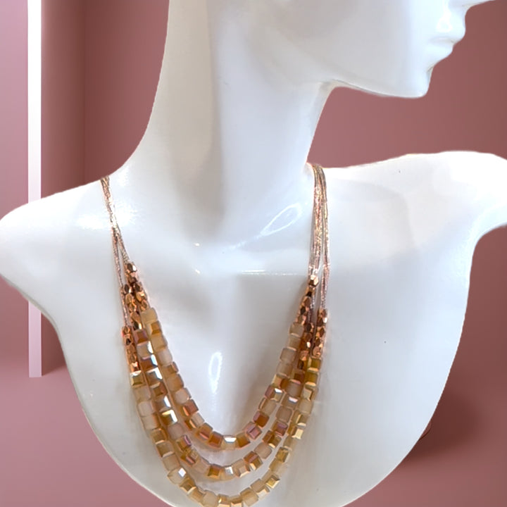 Triple Strands is a rose gold silk triple-strand necklace featuring iridescent Swarovski crystals.